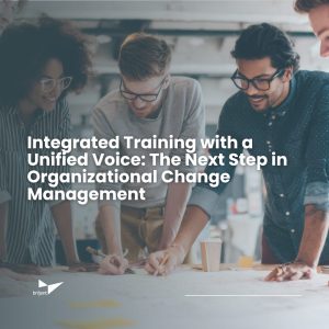 A diverse group of four colleagues stands around a table, collaborating and smiling as they review plans and notes. The text overlay reads: 'Integrated Training with a Unified Voice: The Next Step in Organizational Change Management.' The Briljent logo appears in the bottom left corner.