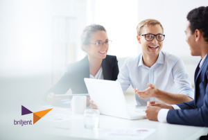 Three business professionals collaborating around a laptop and papers at a conference table